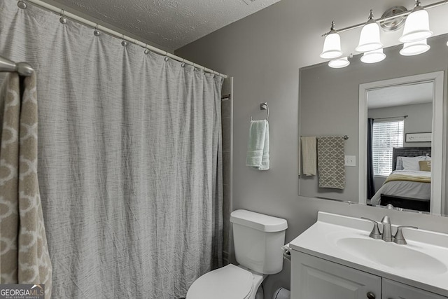 ensuite bathroom with a textured ceiling, vanity, connected bathroom, and toilet