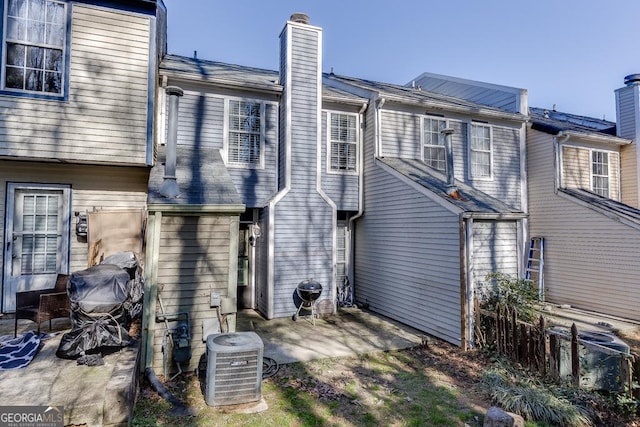 back of property featuring central air condition unit, a chimney, and a patio