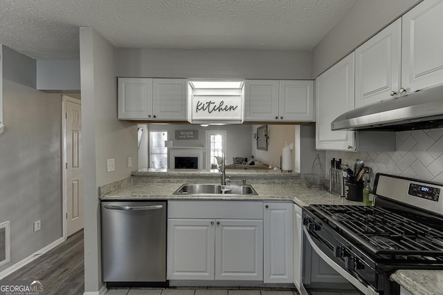 kitchen featuring under cabinet range hood, white cabinetry, appliances with stainless steel finishes, and a sink