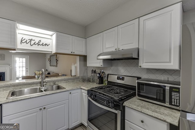 kitchen with backsplash, appliances with stainless steel finishes, white cabinets, a sink, and under cabinet range hood