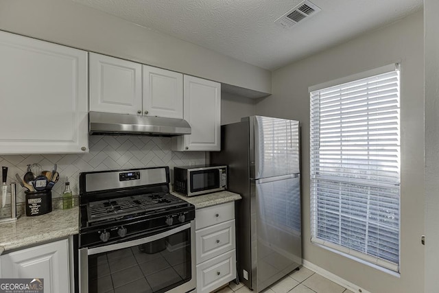 kitchen featuring visible vents, backsplash, appliances with stainless steel finishes, white cabinets, and under cabinet range hood