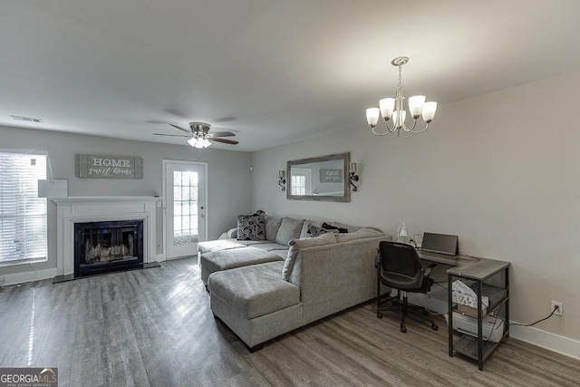 living area with visible vents, a fireplace with raised hearth, baseboards, and wood finished floors