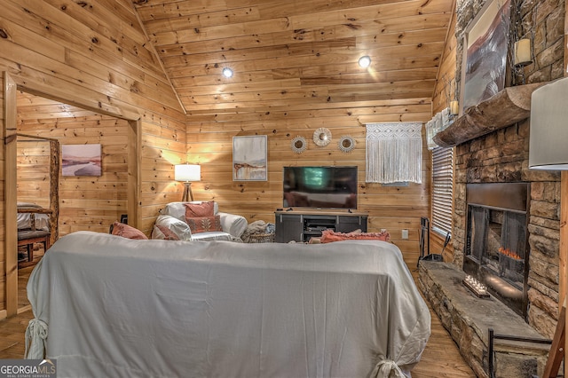 bedroom featuring wood ceiling, wood walls, vaulted ceiling, a stone fireplace, and light wood-type flooring