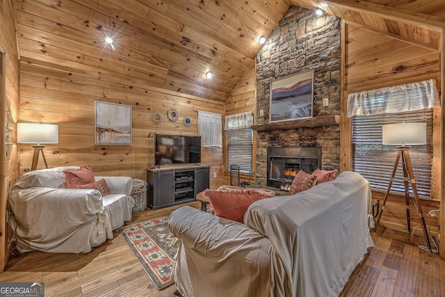 living area with light wood-style floors, wood ceiling, a fireplace, and high vaulted ceiling