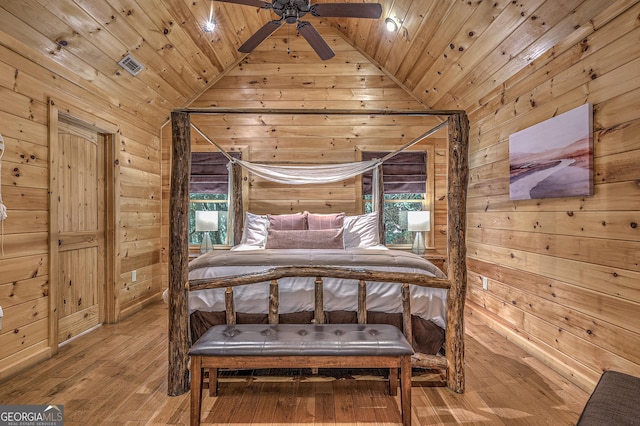 bedroom featuring visible vents, hardwood / wood-style flooring, wood ceiling, vaulted ceiling, and wood walls