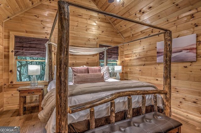 bedroom with vaulted ceiling, wooden ceiling, hardwood / wood-style flooring, and wooden walls