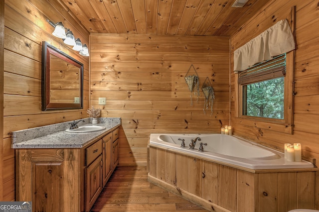 bathroom featuring wood walls, vanity, wood finished floors, wooden ceiling, and a bath