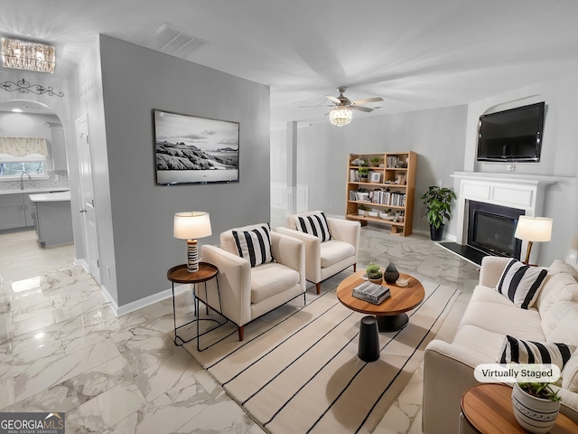 living area featuring arched walkways, visible vents, baseboards, marble finish floor, and a glass covered fireplace