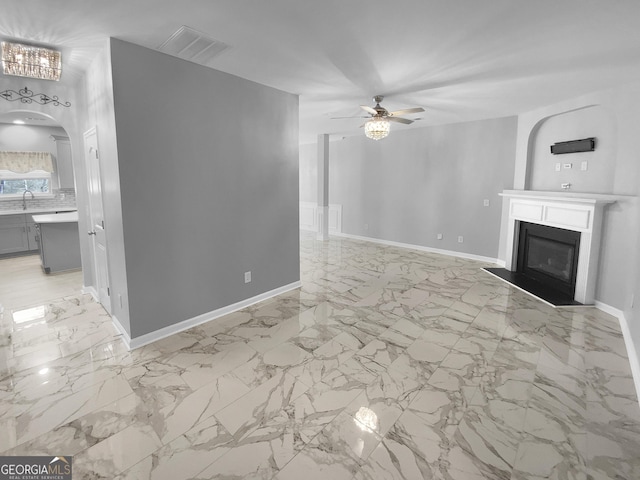 unfurnished living room featuring arched walkways, visible vents, a fireplace with flush hearth, ceiling fan, and a sink