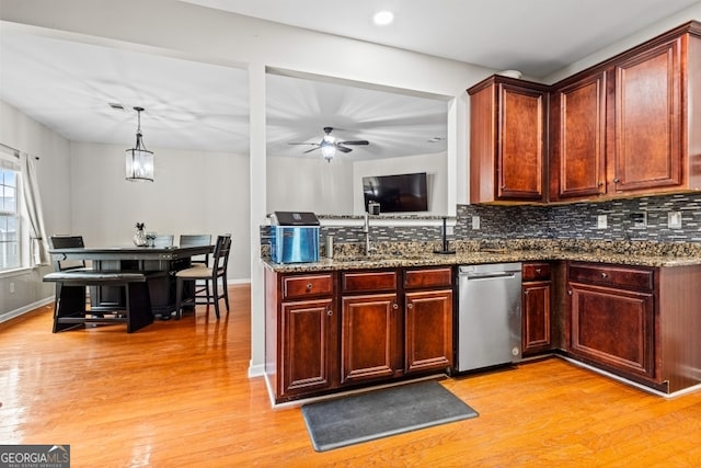 kitchen featuring stainless steel dishwasher, light wood-type flooring, a sink, and decorative backsplash