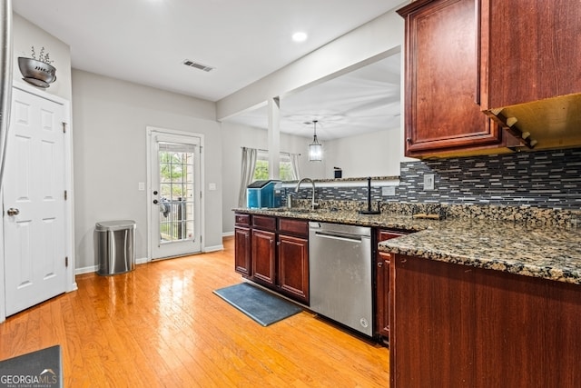 kitchen with light wood finished floors, tasteful backsplash, a sink, dishwasher, and a peninsula