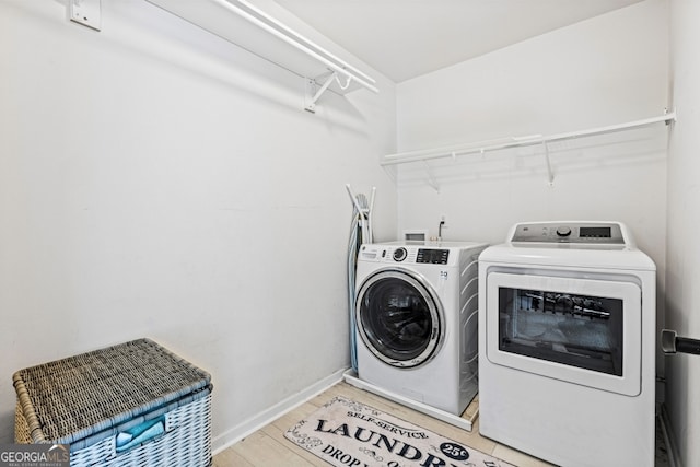 laundry area featuring laundry area, baseboards, washer and clothes dryer, and light wood finished floors