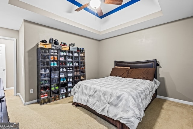 bedroom featuring carpet, a tray ceiling, and baseboards