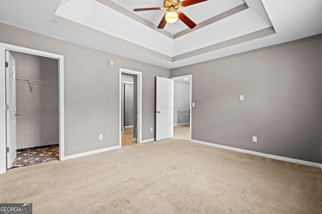 unfurnished bedroom with carpet, baseboards, and a raised ceiling