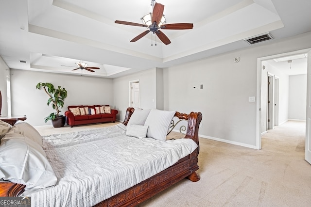 bedroom with a raised ceiling, light colored carpet, visible vents, attic access, and baseboards