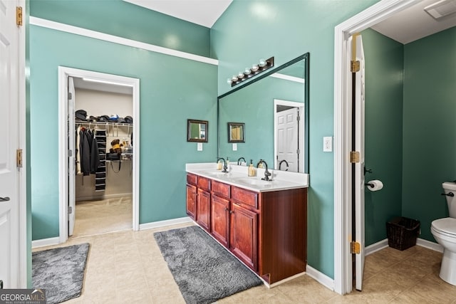 full bath featuring double vanity, visible vents, toilet, a sink, and baseboards