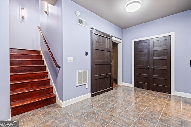 entrance foyer with stairs, a barn door, visible vents, and baseboards