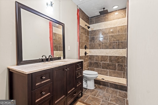 bathroom with tiled shower, vanity, and toilet