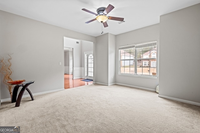 carpeted spare room with visible vents, a ceiling fan, and baseboards