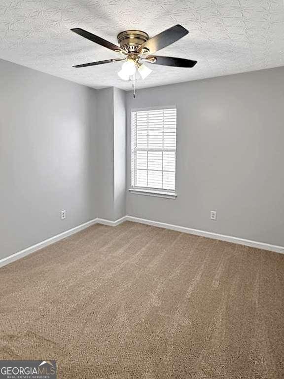 spare room with ceiling fan, carpet flooring, and baseboards