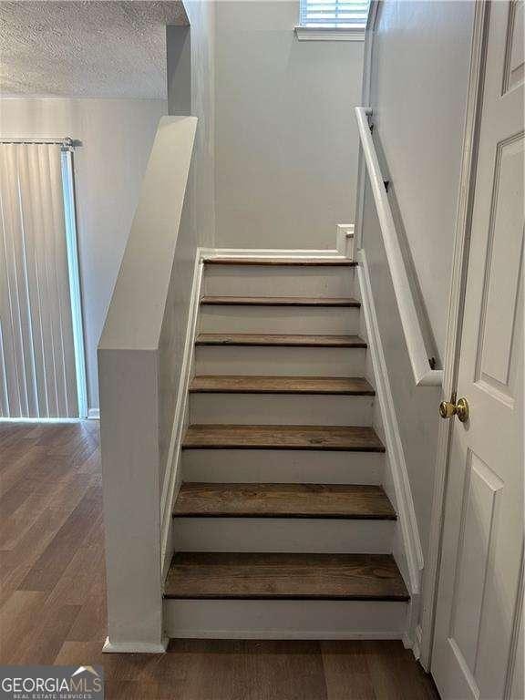 stairway featuring a textured ceiling and wood finished floors