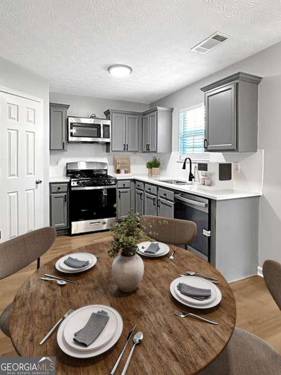 kitchen with stainless steel appliances, light countertops, visible vents, and gray cabinetry