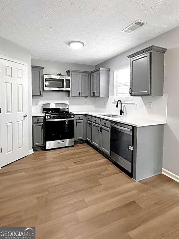 kitchen with visible vents, stainless steel appliances, light countertops, and gray cabinetry