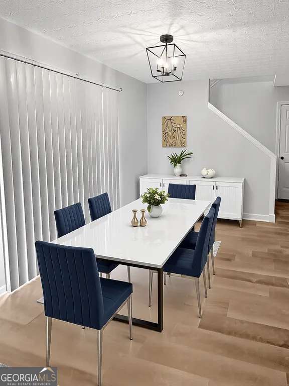 dining room featuring baseboards, a notable chandelier, a textured ceiling, and light wood finished floors