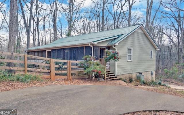 exterior space featuring metal roof, a sunroom, and central air condition unit