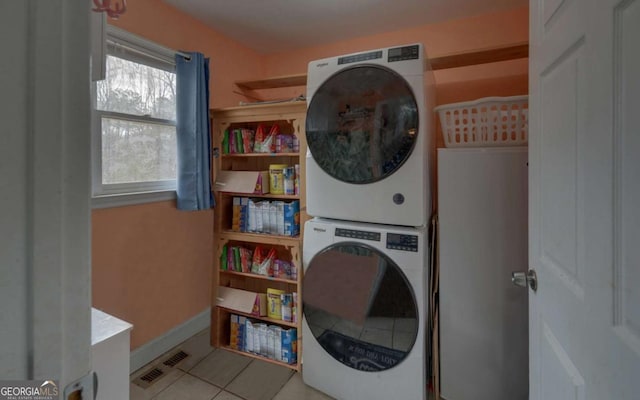 washroom with light tile patterned floors, laundry area, visible vents, baseboards, and stacked washer / drying machine