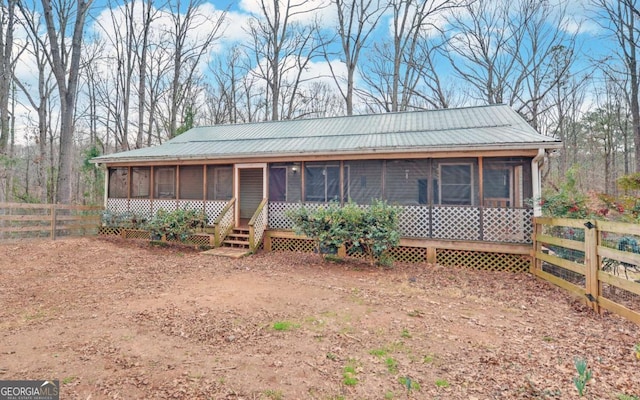 view of front facade with metal roof, fence, and a sunroom