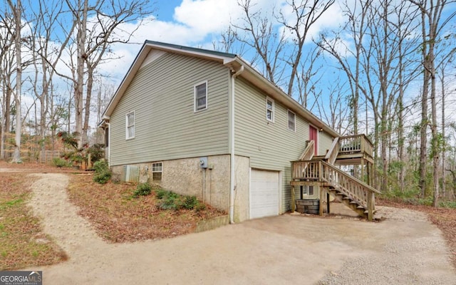 view of home's exterior featuring a garage, driveway, a deck, and stairs