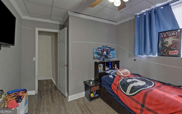 bedroom featuring a paneled ceiling, ornamental molding, ceiling fan, wood finished floors, and baseboards