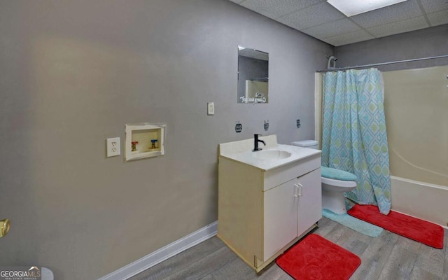 full bath featuring toilet, wood finished floors, shower / bath combo with shower curtain, vanity, and a paneled ceiling