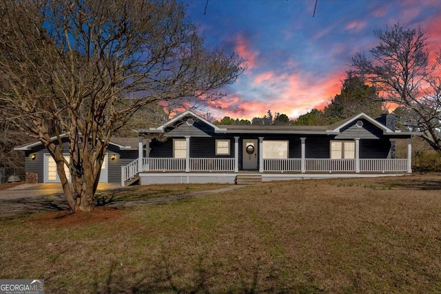 ranch-style home featuring an attached garage, a front lawn, a porch, and concrete driveway