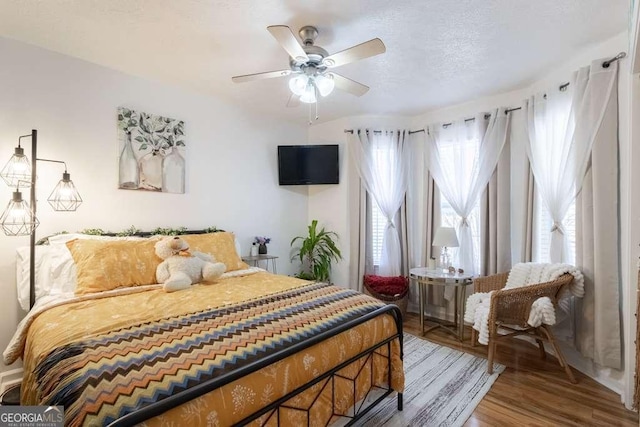 bedroom featuring a textured ceiling, a ceiling fan, and wood finished floors