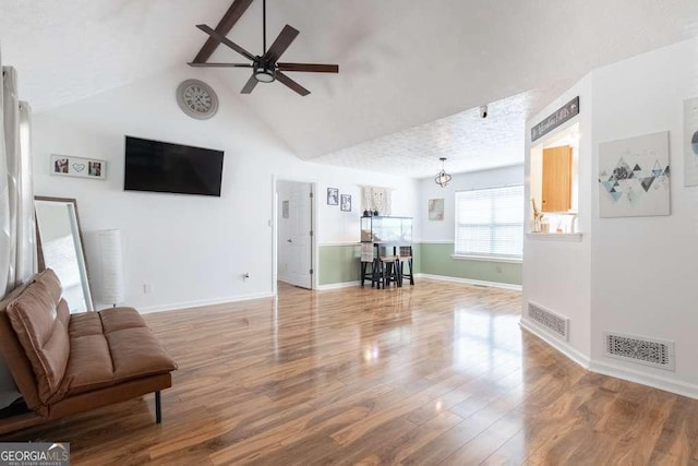 living room featuring visible vents, ceiling fan, baseboards, and wood finished floors