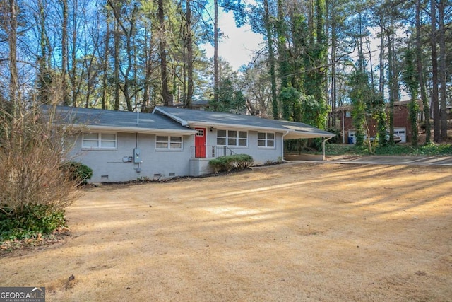 view of front of home with crawl space, dirt driveway, a carport, and brick siding