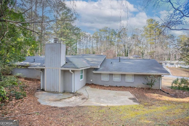 back of property featuring a chimney and a patio area