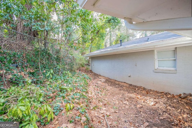 view of side of home with brick siding and fence