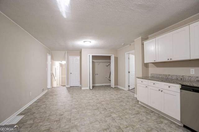 kitchen featuring visible vents, baseboards, white cabinetry, stainless steel dishwasher, and light stone countertops