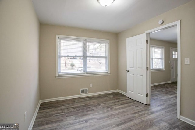 unfurnished room featuring baseboards, visible vents, and wood finished floors