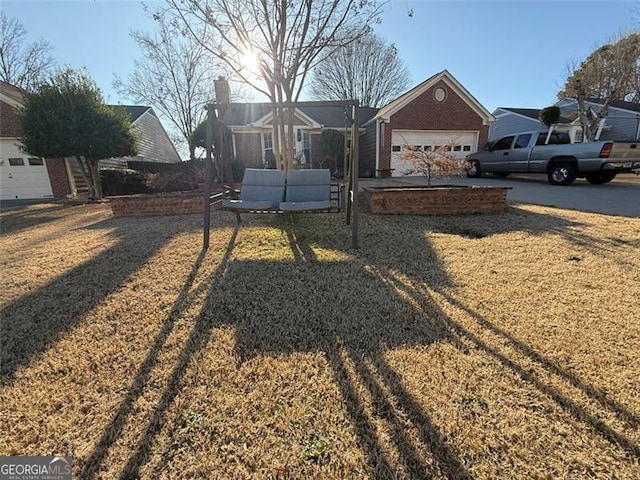 view of front of property featuring a garage, a front lawn, and brick siding