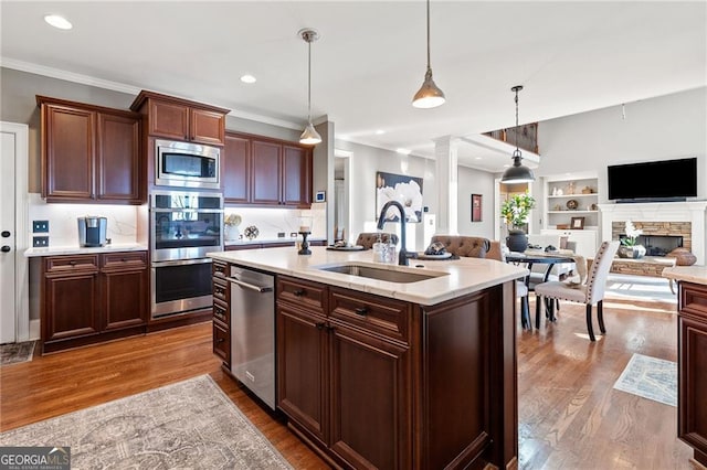 kitchen with appliances with stainless steel finishes, light countertops, dark wood-type flooring, and a sink