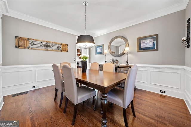 dining room featuring crown molding, wood finished floors, and a wainscoted wall