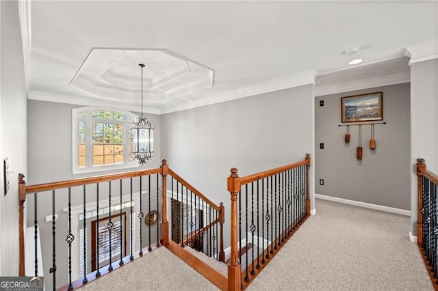 corridor featuring a tray ceiling, a notable chandelier, an upstairs landing, and carpet floors