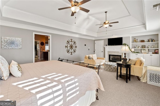 bedroom with visible vents, a tray ceiling, a fireplace, ornamental molding, and light colored carpet