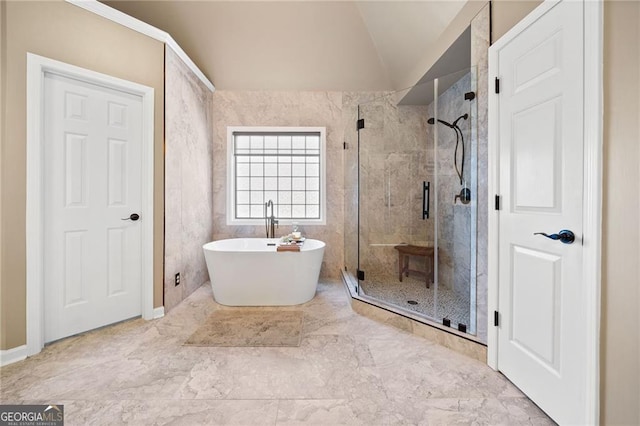 full bath with a freestanding tub, marble finish floor, a shower stall, and vaulted ceiling