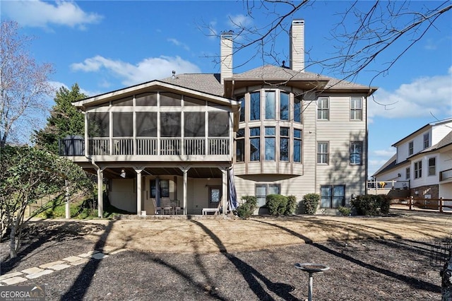 back of house with a sunroom and a chimney