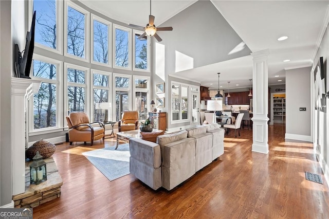 living area with a ceiling fan, ornamental molding, dark wood-style flooring, and ornate columns